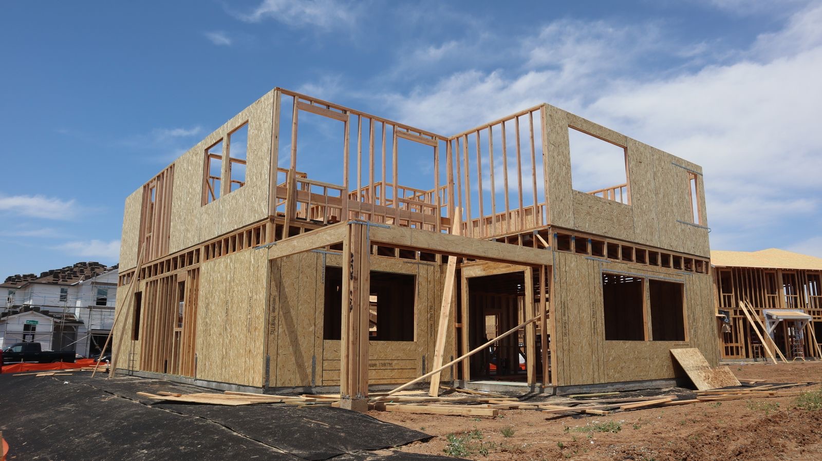 Two-story wood-framed house under construction on a clear day