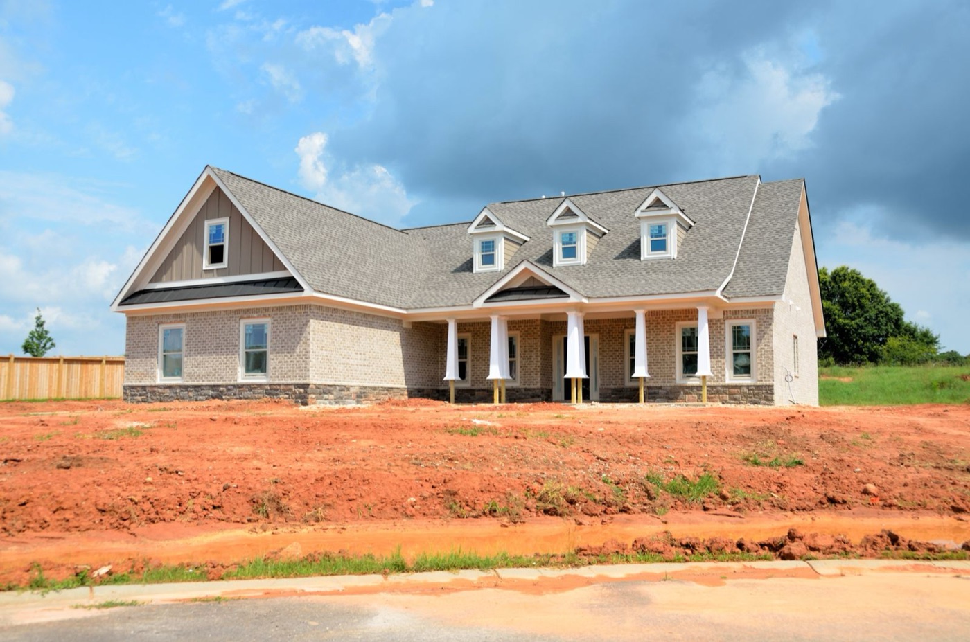 New brick house on a freshly graded lot beside a new road