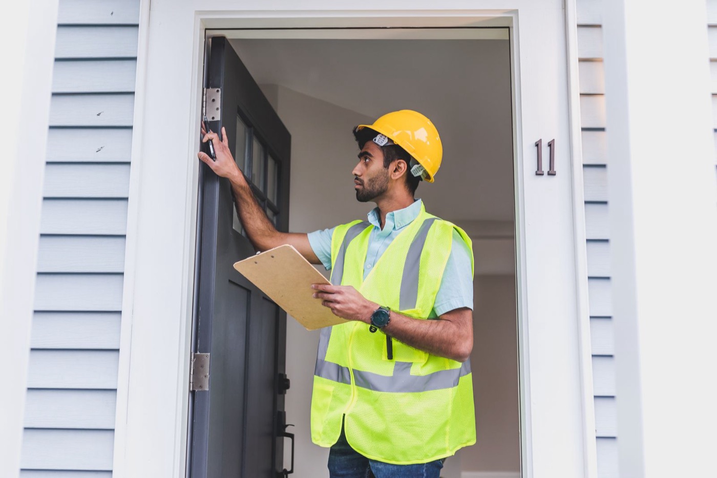 Inspector in a safety vest checking a door frame