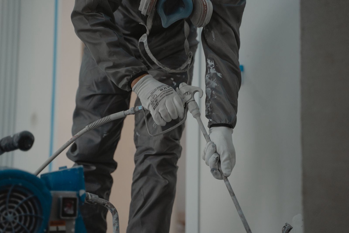 Worker in protective gear operating a spray rig indoors